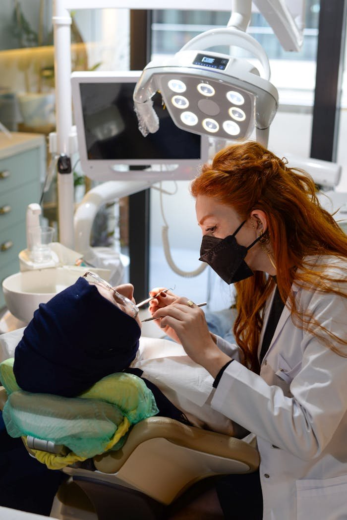Mastering the First Impression: Your intriguing post title goes here A female dentist with red hair treating a patient in a dental clinic. Professional healthcare setting.