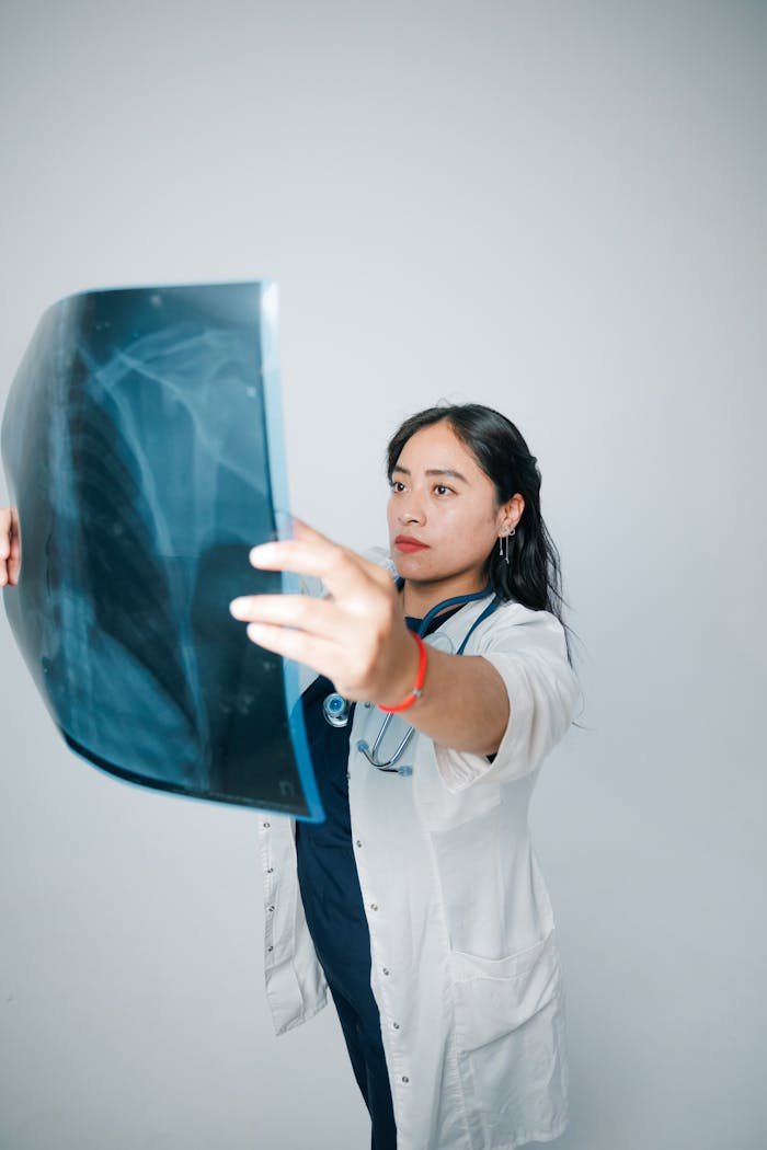 The Art of Drawing Readers In: Your attractive post title goes here A female doctor in a white coat examines a patient's X-ray image against a neutral background.