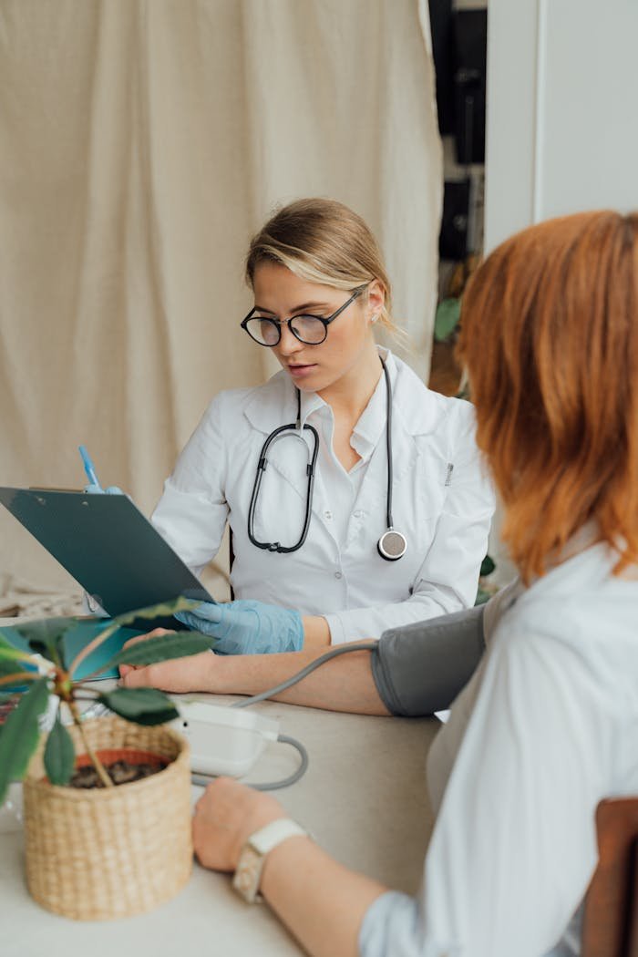 about-us A female doctor checks a patient's blood pressure during a routine consultation in a clinic.