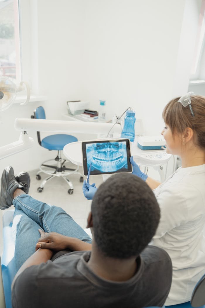 Dentist showing patient a dental x-ray on a tablet in a modern clinic setting.