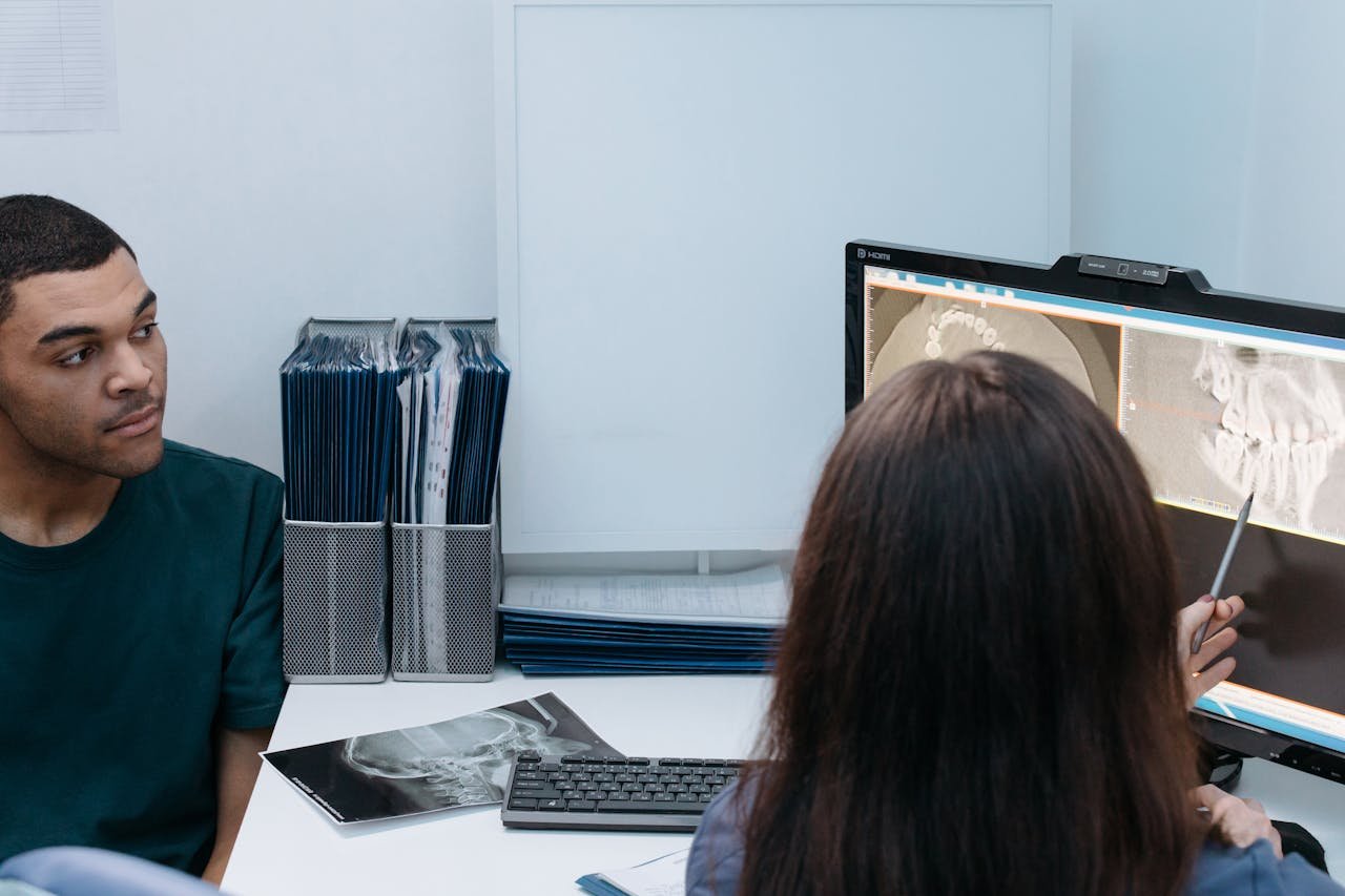 Dentist and patient discussing dental X-ray results in a clinic setting.